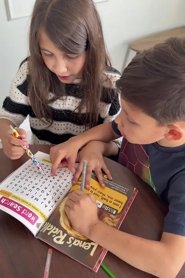 Two children doing the puzzle pages in Who Will Save Me From Boredom